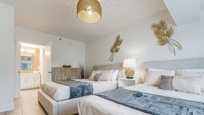 A modern bedroom with two beds, a bedside table with a lamp, and a decorative wall piece.