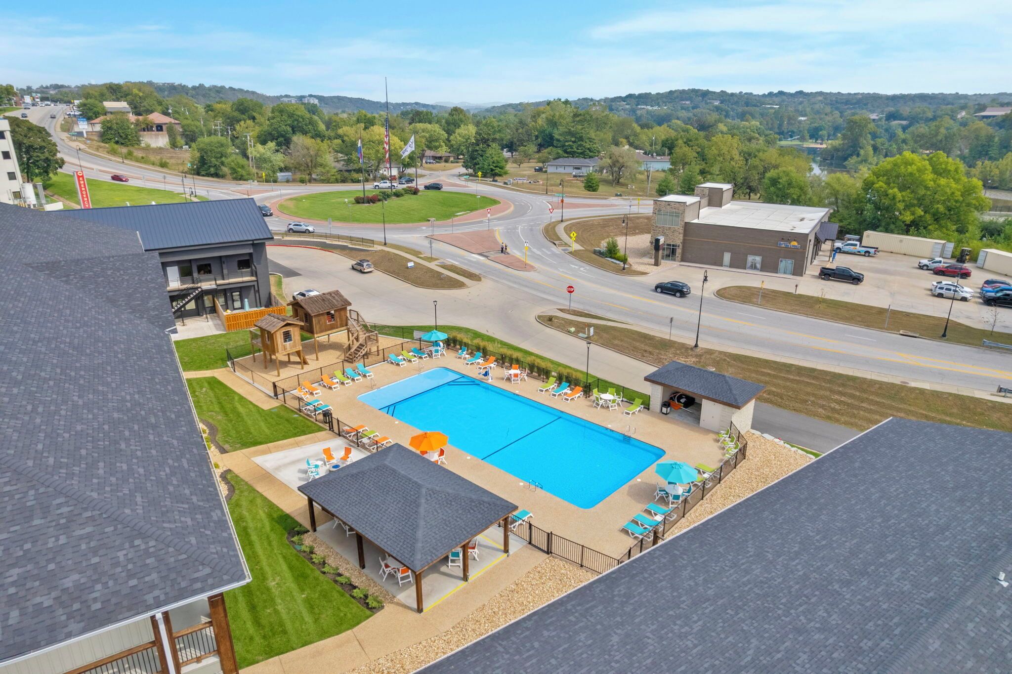 A swimming pool with lounge chairs, a covered seating area, and a view of a road and surrounding landscape.