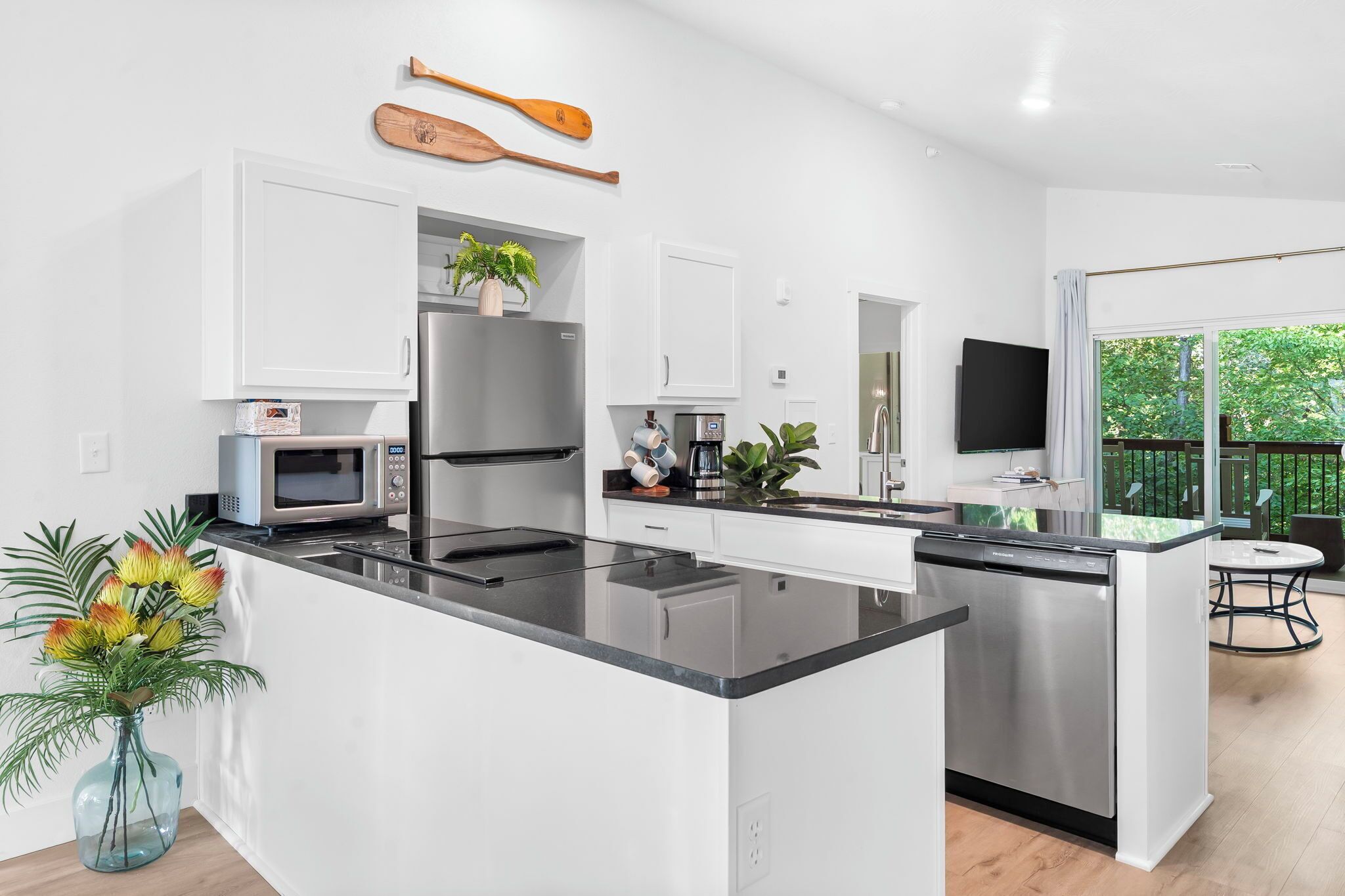 A modern kitchen with white cabinetry, a stainless steel refrigerator, a built-in oven, and a coffee maker.