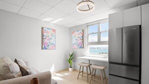 Una cucina moderna con un frigorifero capiente, un'area pranzo con un divano e due sgabelli da bar, e una finestra vista mare.