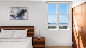 Una camera da letto con un letto, un comodino, una lampada, un'opera d'arte, una finestra e un armadio.