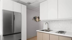 Una cucina moderna con elettrodomestici in acciaio inossidabile, zoccolo di piastrelle bianche e mobili beige.