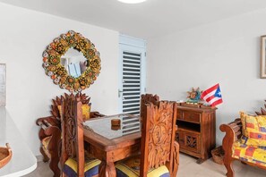 Un comedor con una mesa y sillas de madera, un tapiz decorativo y una bandera.
