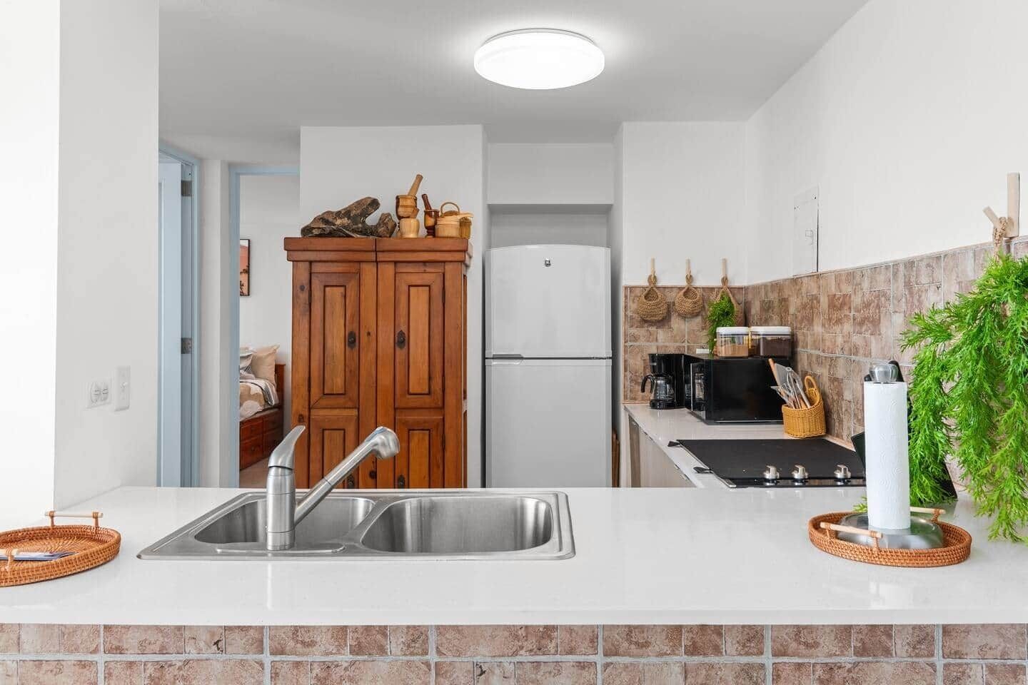Una cocina moderna con un lavamanos de acero inoxidable, armarios de madera, un microondas y una estufa a gas.