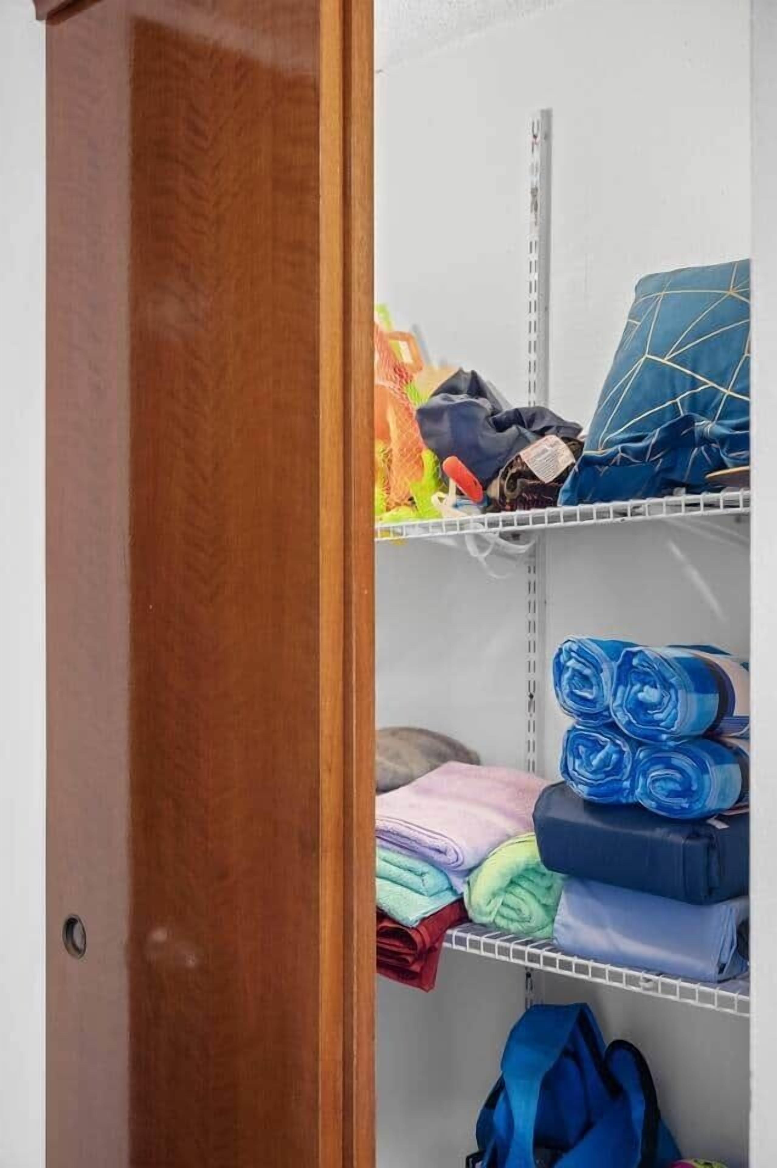 Un espacio de almacenamiento con estantes que contienen ropa doblada y una bolsa azul.