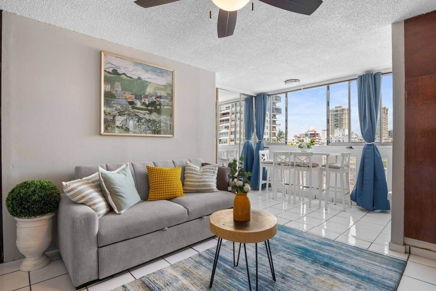 A modern living room with a grey sofa, a round coffee table, and a painting on the wall.