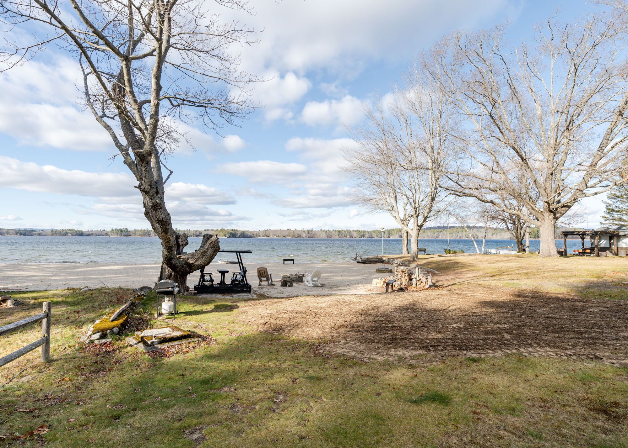 A lakeside campsite with a golf cart, picnic table, and benches.
