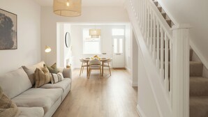 A spacious living room with a sofa, a dining table, and a staircase. - Beautifully Refurbished Terrace – Just a 15-Minute Riverside Walk into York (York)