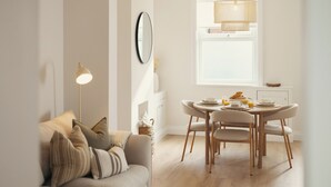 A cozy living room with a sofa, a dining table with chairs, a lamp, and a window with natural light. - Beautifully Refurbished Terrace – Just a 15-Minute Riverside Walk into York (York)