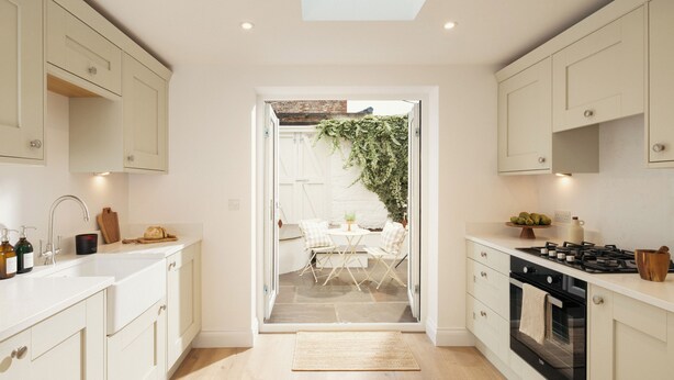 A modern kitchen with white cabinetry, a gas stove, and a view into a dining area with a table and chairs. - Beautifully Refurbished Terrace – Just a 15-Minute Riverside Walk into York (York)