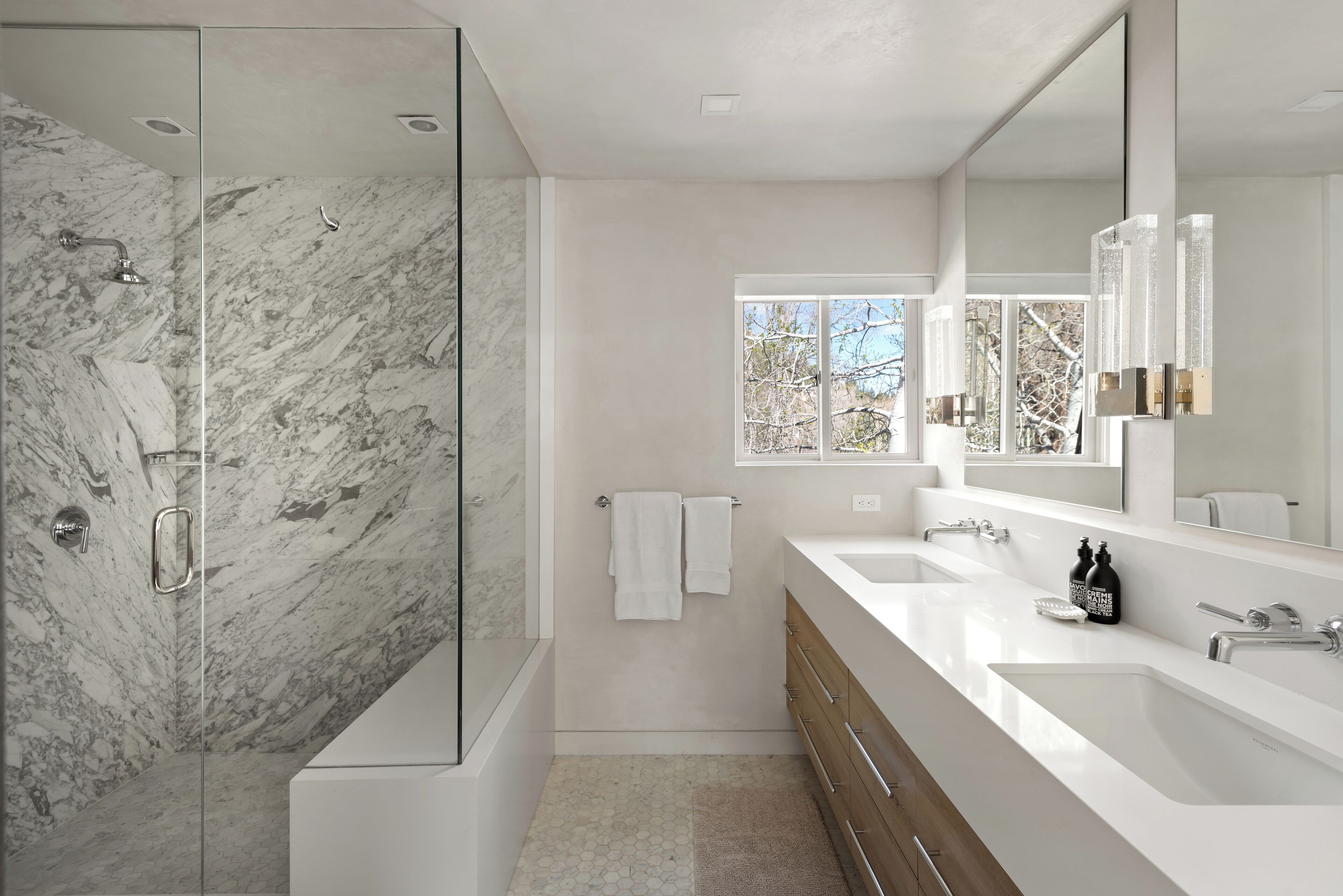 A modern bathroom with a glass-enclosed shower, a large mirror, and a dual sink vanity.
