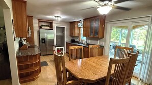 A spacious kitchen with wooden cabinets, a built-in refrigerator, and a dining area with a large wooden table and chairs. - Par-fect Escape on Lake Windsor Golf Course (Windsor)