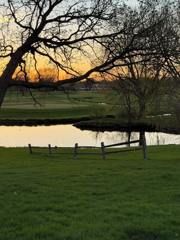 A serene landscape with a pond, a wooden fence, and a building in the background. - Par-fect Escape on Lake Windsor Golf Course (Windsor)