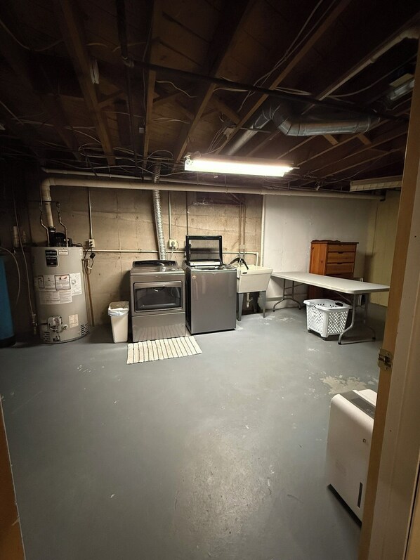 A basement with a kitchenette, a water heater, a washing machine, and a laundry basket. - Par-fect Escape on Lake Windsor Golf Course (Windsor)