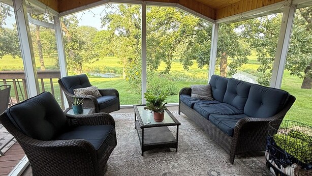 A covered patio area with wicker furniture, a ceiling fan, and a view of a green landscape. - Par-fect Escape on Lake Windsor Golf Course (Windsor)
