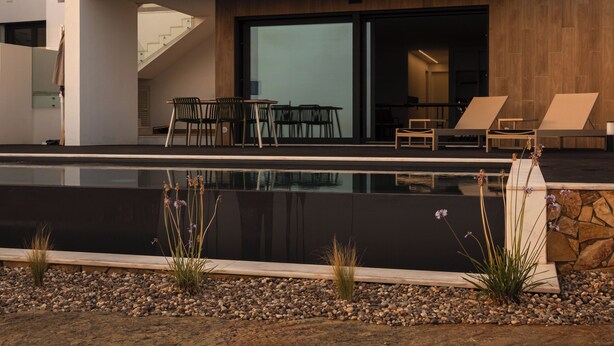 Un bâtiment moderne à deux étages, doté d’un balcon, d’un espace extérieur aménagé pour s’asseoir et d’une piscine.
