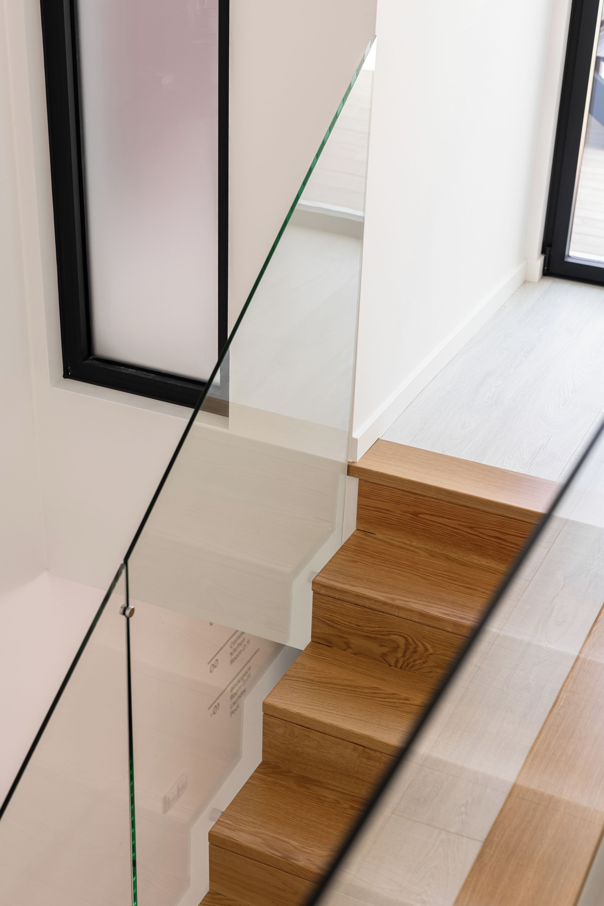 Una escalera con barandillas de vidrio y peldaños de madera.