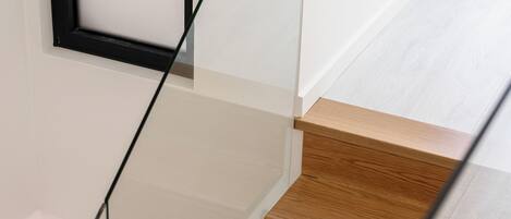 Una escalera con barandillas de vidrio y peldaños de madera.