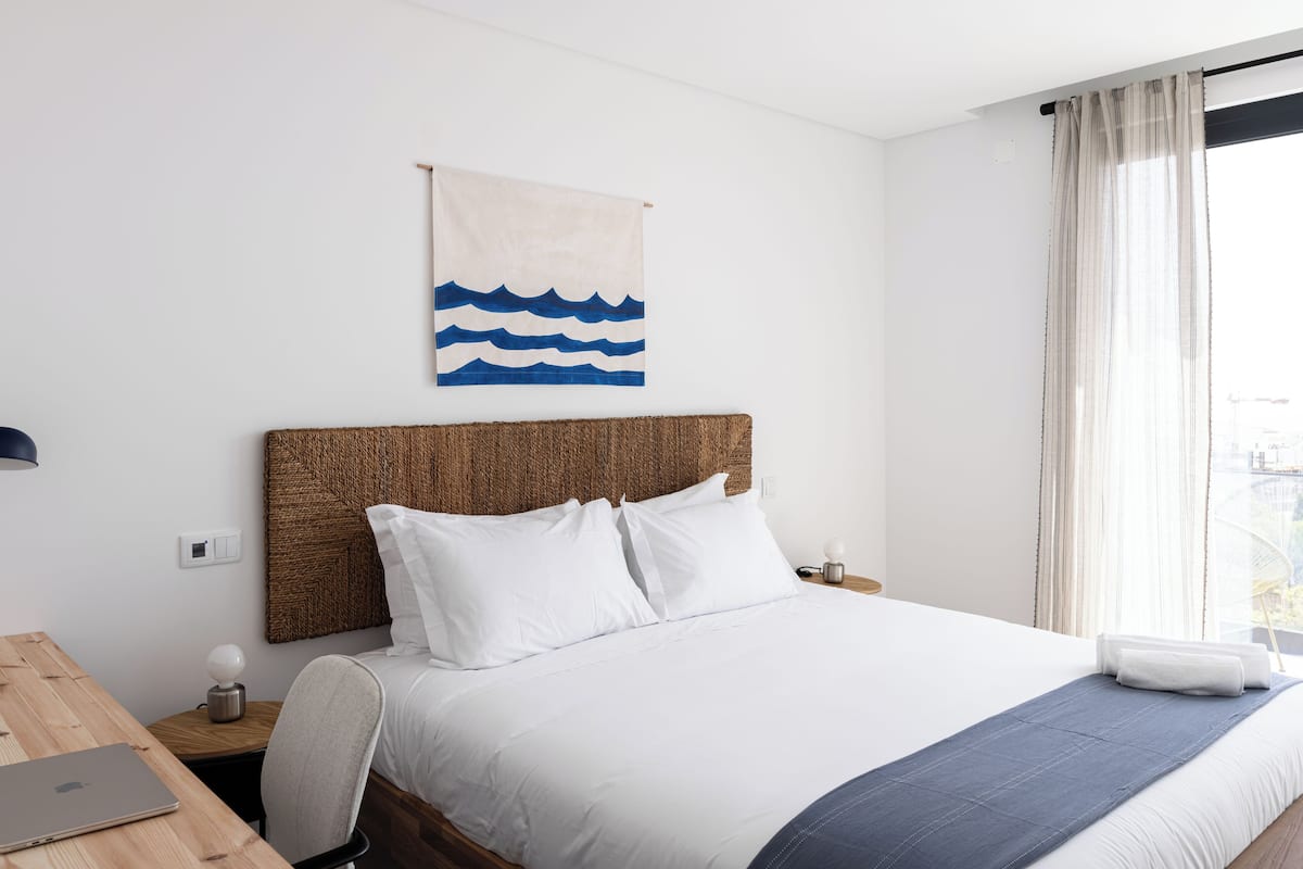 Ein ordentlich eingerichtetes Hotelzimmer mit einem Bett, einem Schreibtisch und einem Laptop.