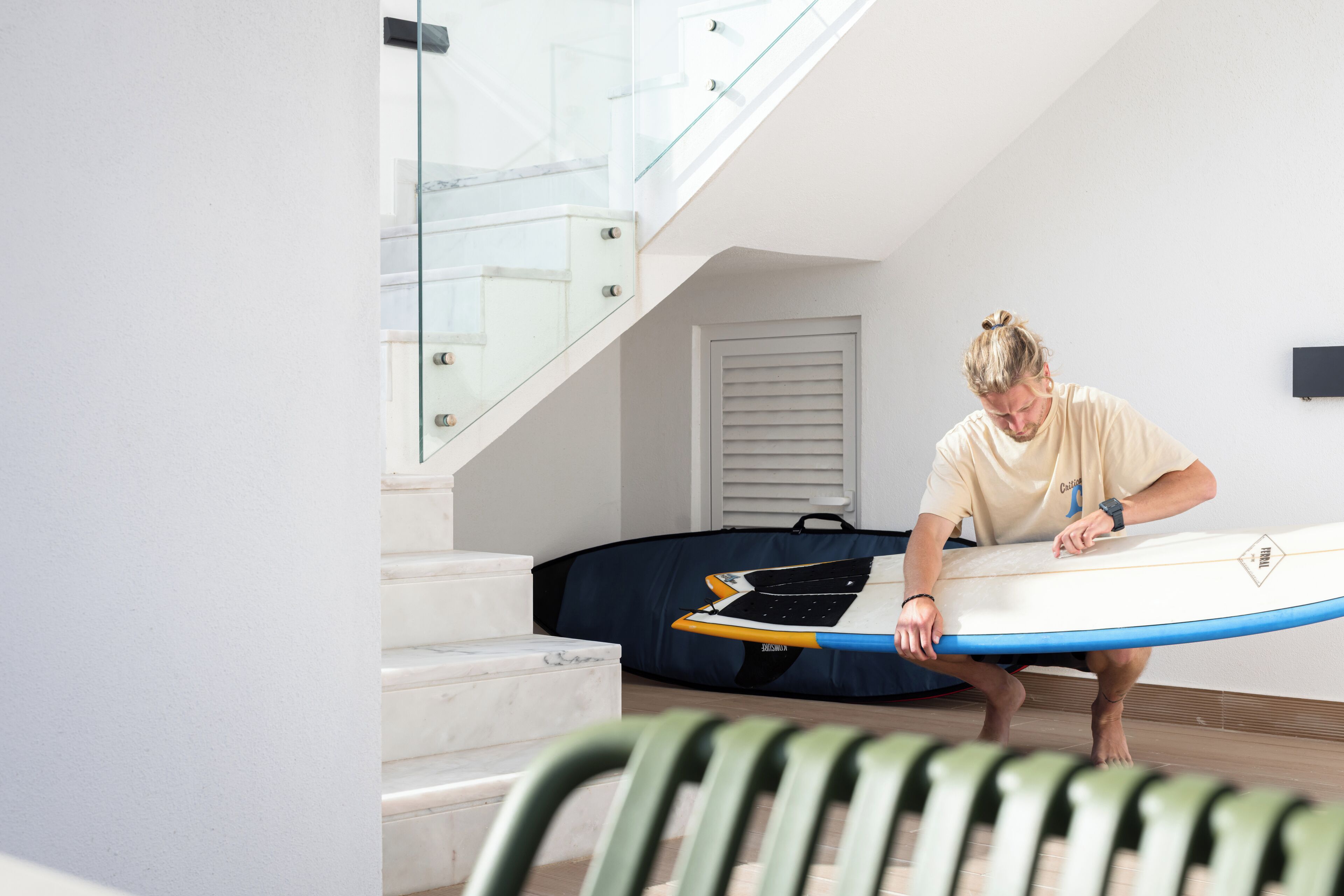 A person carrying a surfboard down a staircase.