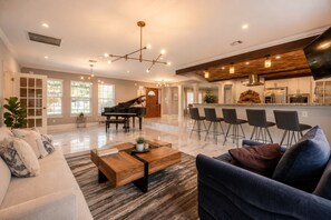 A spacious living room with a grand piano, a coffee table, and a blue sofa.
