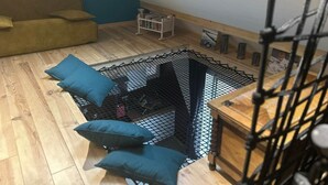 A loft bedroom with a sloped ceiling, a wooden floor, a bed with a black net canopy, and a small white table with books. - Gite with Spa (Arras-en-Lavedan)