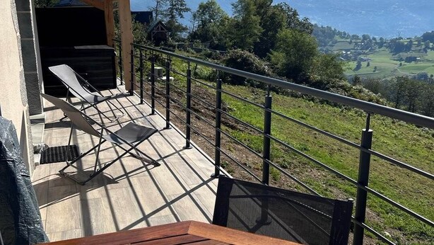 A wooden deck with a table and chairs, overlooking a mountainous landscape. - Gite with Spa (Arras-en-Lavedan)