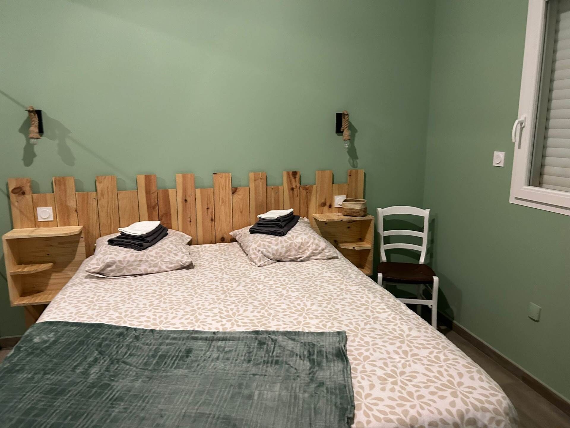 Une pièce comprenant un lit, deux tables de chevet, une chaise et une fenêtre.