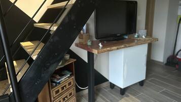 Een moderne woonkamer met een trap, een flatscreen televisie en een houten bureau.