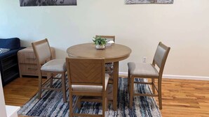 A dining area with a round table and four chairs, a small plant on the table, and two wall-mounted artworks depicting horses and an eagle. - NYC Skyline Apartment (Weehawken Township)