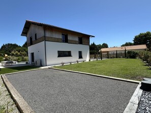 Een modern huis met twee verdiepingen, een plat dak, een verharde oprit en een verzorgd gazon.