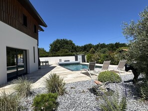 Een modern huis met een zwembad, buitenmeubilair en een tuin.