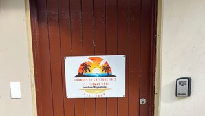 A brown door with a sign that reads "CHANGES IN LATITUDE 18.3 ST. THOMAS USVI EST. 2025". - Changes in Latitude 18.3 spacious Mahogany Run condo with ocean views. (St Thomas)