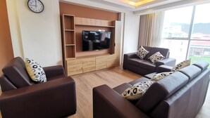 Ein modernes Wohnzimmer mit Flachbildfernseher, Holzregalen und einer Sofagarnitur.