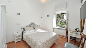 A bedroom with a bed, bedside table, chair, and a window with a view of a stone bridge. - B&B La Cascata   Camera Amalfi (AMALFI)