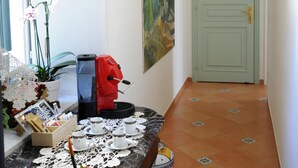 A hallway with a coffee machine, cups, and a table with a lace doily. - B&B La Cascata   Camera Amalfi (AMALFI)