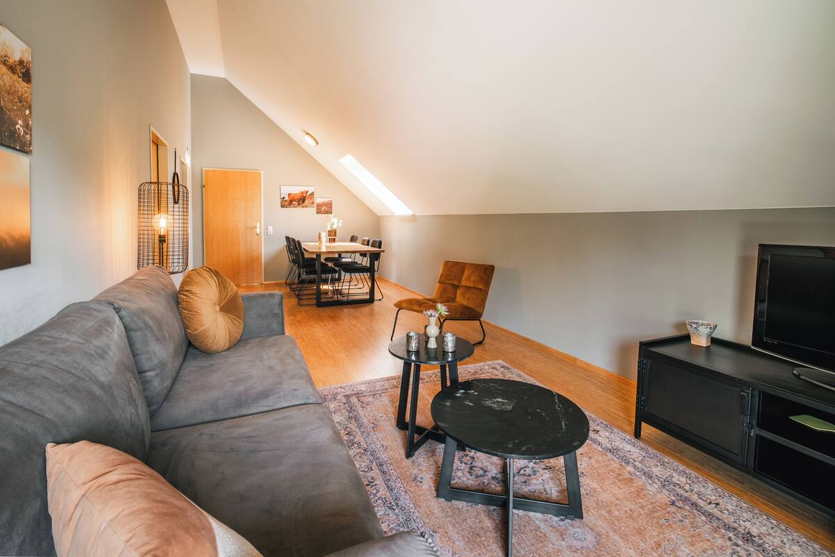Ein modernes Loft-Apartment mit Essbereich, einer Couch, einem Couchtisch und einem Fernseher.