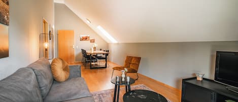 Un moderno apartamento estilo loft con comedor, sofá, mesa de centro y televisor.