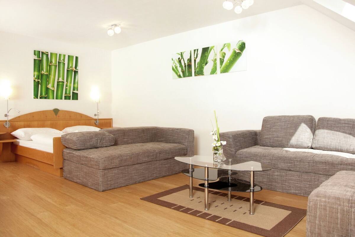 Ein modernes Hotelzimmer mit einem Bett, zwei Sofas, einem kleinen Tisch und Wandbildern.