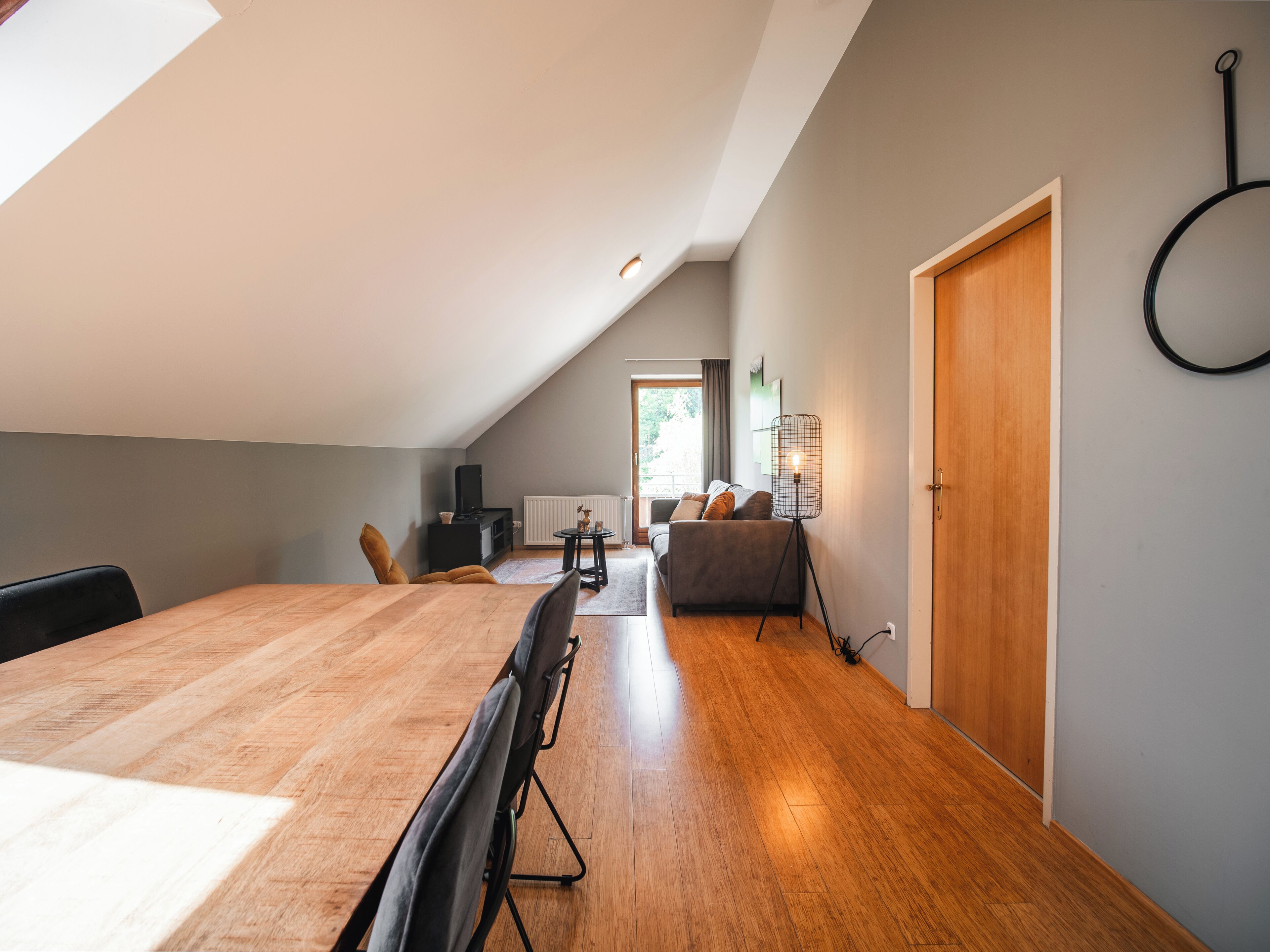 A modern loft apartment with a dining area, a sofa, and a ceiling fan.