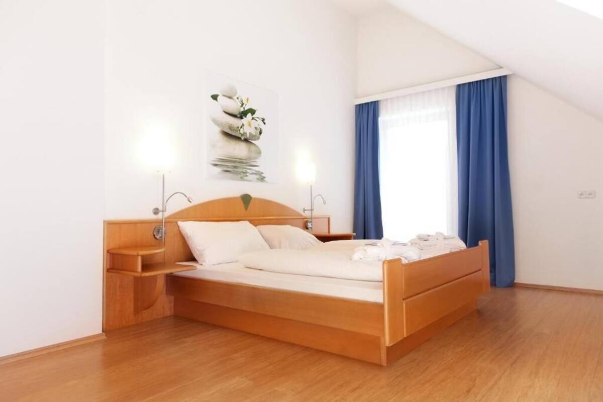 Ein Schlafzimmer mit einem hölzernen Bett, Nachttischen, einer Wandlampe und einem Fenster mit blauen Vorhängen.