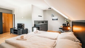 Ein modernes Hotelzimmer mit einem großen Bett, einem Schreibtisch, einer Küchenzeile und einem Fernseher.
