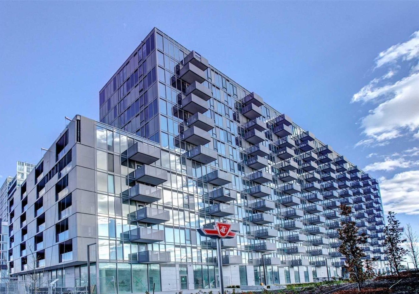A modern high-rise building with multiple balconies and a glass facade.