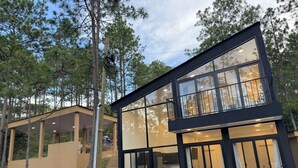 Une maison moderne à deux étages, dotée de grandes fenêtres et d’un balcon.