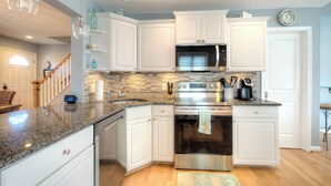A modern kitchen with white cabinetry, granite countertops, stainless steel appliances, and a built-in microwave. - Bay Avenue Bliss, Newly Updated, Spacious Yard, OCNJ South Shore (Ocean City)