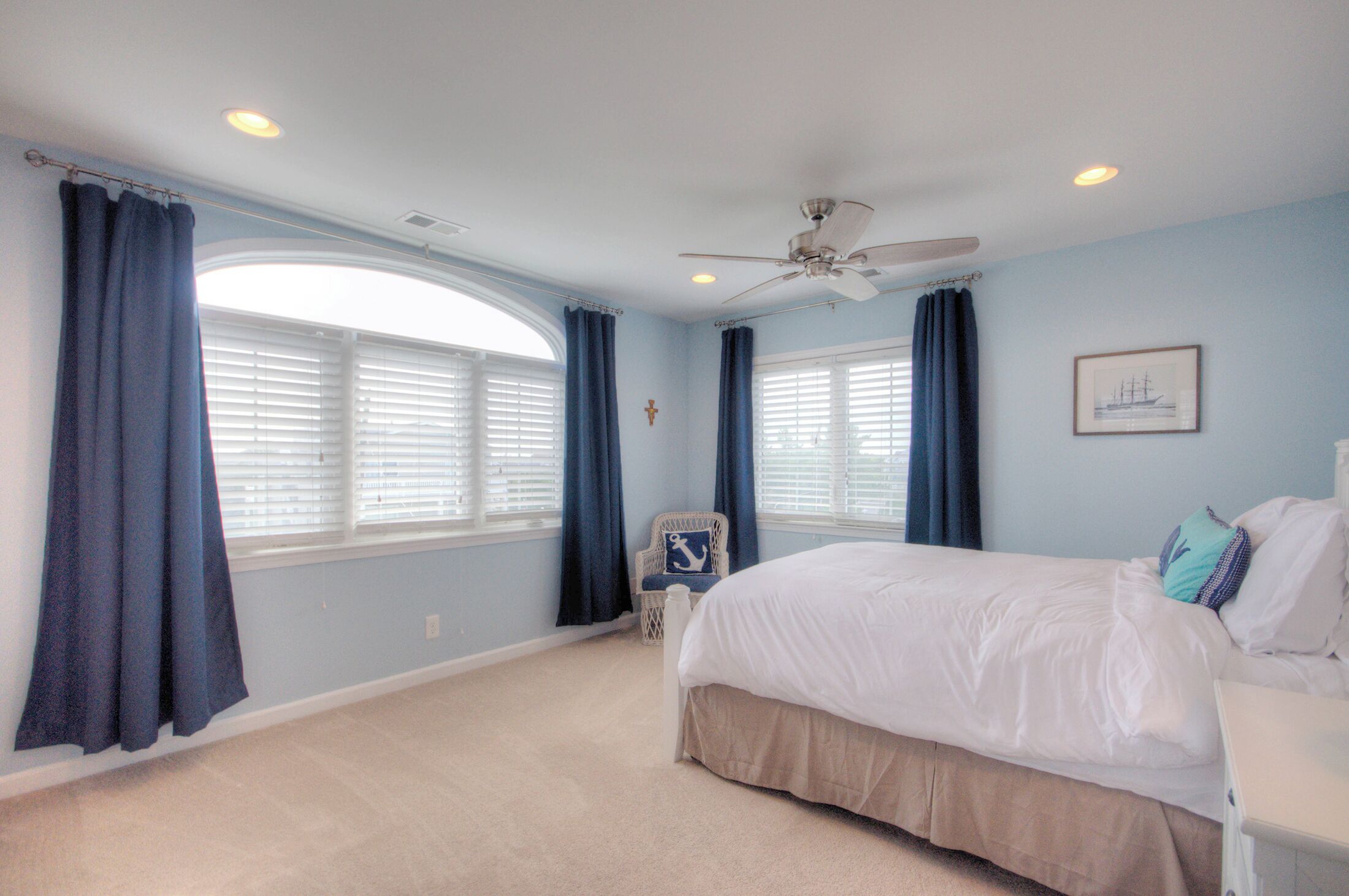 Une chambre à coucher avec un lit, une chaise et un ventilateur de plafond.