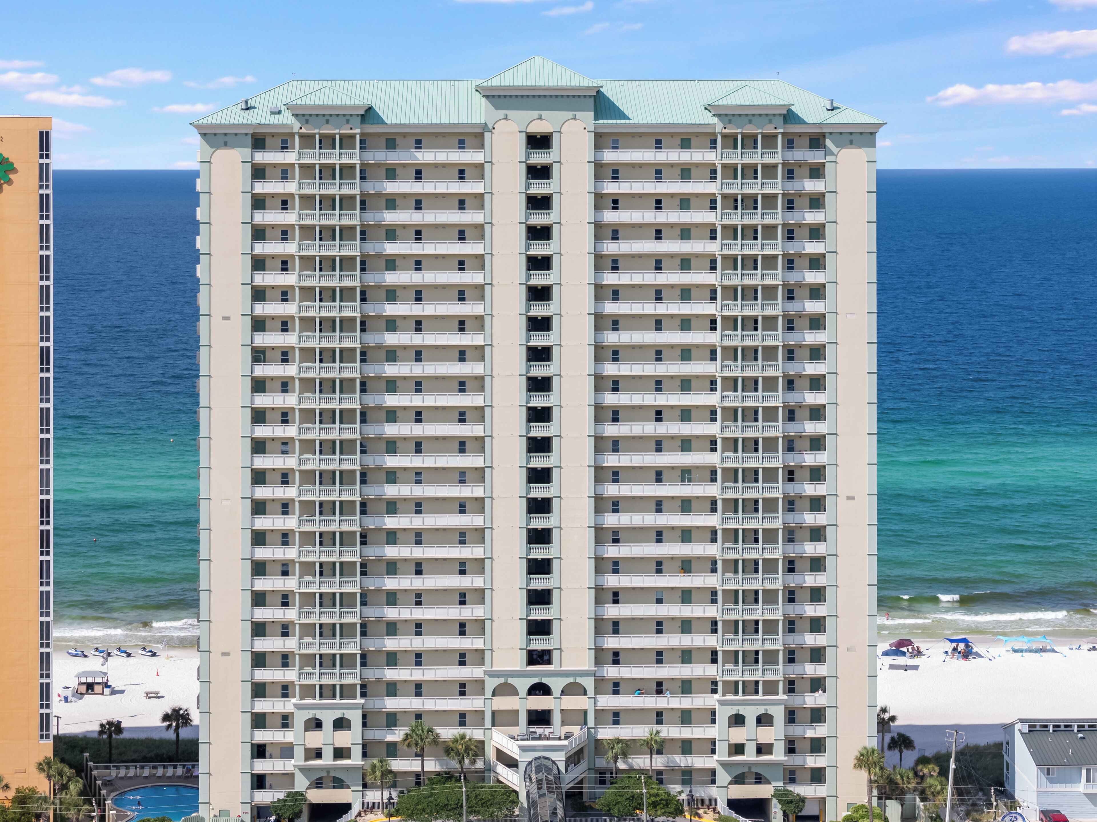 Un hôtel de grande hauteur doté de nombreux balcons, d’un espace piscine et offrant une vue sur la plage.