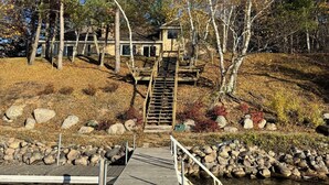 A wooden dock leading to a house with a staircase. - Lakefront Home on Crosslake - Perfect Location for Fun in the Lakes Area! (Crosslake)