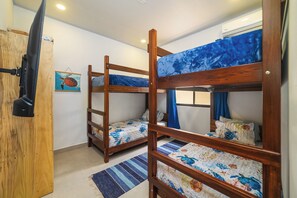 Ein Schlafzimmer mit Etagenbetten, Holzrahmen, einem blauen Vorhang und einem Wandbild mit Schildkrötenmotiv.