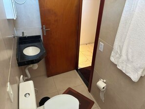 Ein kleines Badezimmer mit Toilette, Waschbecken und einem Handtuch an der Wand.